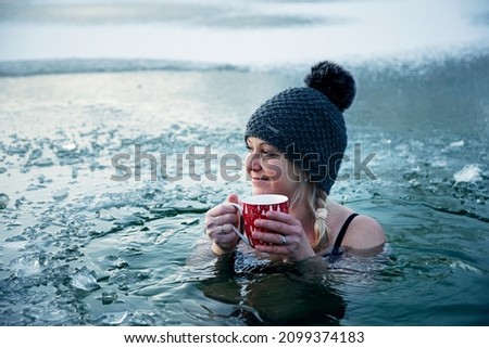 Ice hole swimming, Girl with christmas cup of hot tea in a frozen lake, winter challenge.