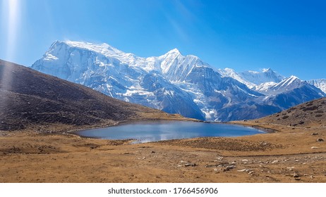 Ice lake, as part of the Annapurna Circuit Trek detour, Himalayas, Nepal. Annapurna chain in the back, covered with snow. Clear weather, dry grass, snowy peaks. Freedom, solitude, chill and relaxation