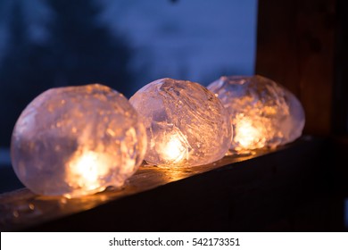 Ice lanterns with flickering fire of a candle on the railing of a wooden house in the mountains. Winter craft
 - Powered by Shutterstock