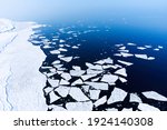 Ice melting in blue sea water, view from above photographed by drone