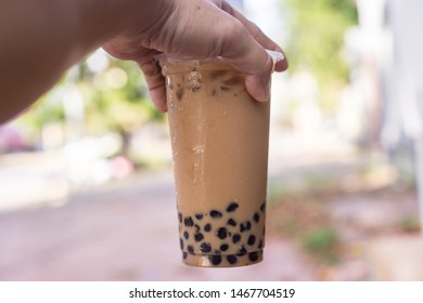 Ice Milk Tea With Bubble Boba In Plastic Glass In Hand Blur Background Are Green Tree And Leaf, Taiwan Ice Milk Tea Fresh Drink 