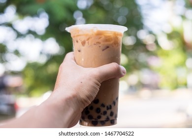 Ice Milk Tea With Bubble Boba In Plastic Glass In Hand Blur Background Are Green Tree And Leaf, Taiwan Ice Milk Tea Fresh Drink 