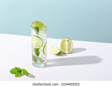 Ice and mojito in a glass lie on the table with a strong shadow