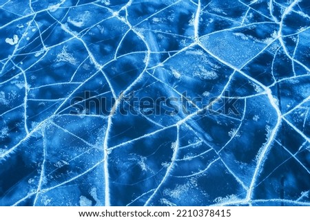 Ice on a frozen river. Background texture of blue ice with cracks in the snow. drone top view.