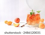 Ice peach tea or cocktail with mint and apricots, a recipe for a refreshing summer drink. Two glasses with peach fruit lemonade on light table, detox diet and weight loss concept, menu for restaurant