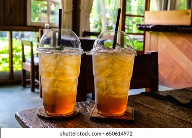 Ice peach tea in plastic cup on wooden table in coffee shop.