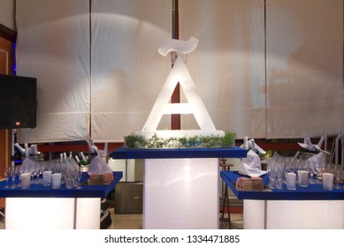 Ice Sculpture In The Shape Of The Letter A With Surrounding Drinks Table.