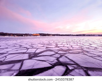 Ice sheets on sea in winter at sunrise on early Scandinavian morning with purple and pink sky in Swedish capital Stockholm with light clouds in the sky - Powered by Shutterstock