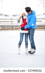 Ice Skating Couple On Date In Love Iceskating And Embracing. Young Couple Embracing On Ice Skates Outdoors On Open Air Rink In Snowy Winter Landscape. Multiracial Couple, Asian Woman, Caucasian Man.