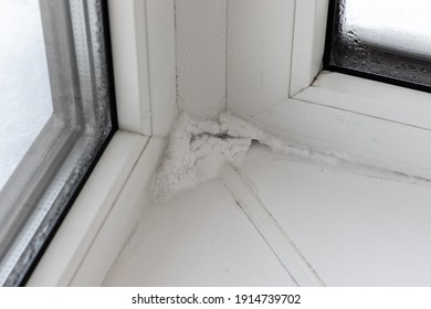 Ice, snow and condensate inside in corner of plastic window in winter. Poor warm isolation concept. Consequences of incorrect installation of window frames. Selective focus