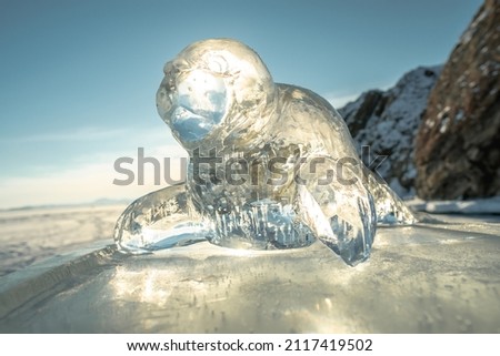 Ice transparent sculpture of a seal in the rays of the sun. Winter art is the art of nature on Lake Baikal.