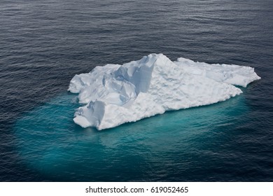 An Iceberg Floats Above And Below The Ocean Surface.