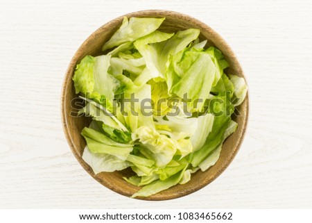 Iceberg lettuce table top fresh torn salad leaves in a wooden bowl isolated on grey wood background
