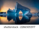 Iceberg in the ocean at dawn. Iceberg reflection in water. Beautiful iceberg in ocean water. Iceberg at dawn landscape