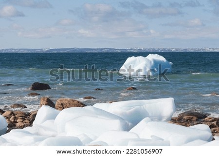 Iceberg on a rocky shoreline in Newfoundland and Labrador, Canada.