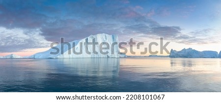 Iceberg at sunset. Nature and landscapes of Greenland. Disko bay. West Greenland. Summer Midnight Sun and icebergs. Big blue ice in icefjord. Affected by climate change and global warming.