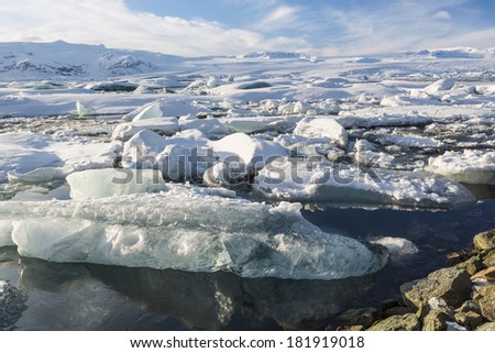 Icebergs crammed in the outlet of Jokulsarlon glacial lagoon with Breidamerkurjokull glacier behind on a sunny winter's afternoon in Iceland