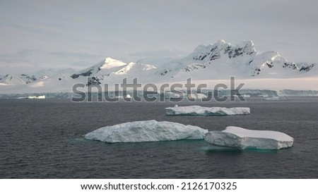 Icebergs and glaciers in Antarctica. Beautiful blue iceberg with mirror reflection floats in open ocean. Global Climate changes video - the glaciers are warming and melting faster.