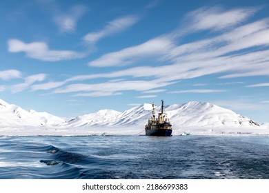 Icebreaker at anchor in the arctic waters of Svalbard, a Norwegian archipelago between mainland Norway and the North Pole. Crisp blue sky and snowy mountain background. - Shutterstock ID 2186699383