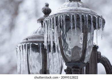 Ice-covered Street Light With Icicles, Close Up. Icing  City Park On A Winter Day After Freezing Rain In Mykolaiv. Blurred Background.