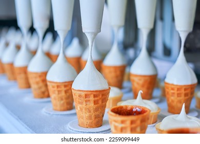 Ice-cream dairy factory - conveyor belt with icecream cones at modern food processing factory. Manufacturing, dairy industry.