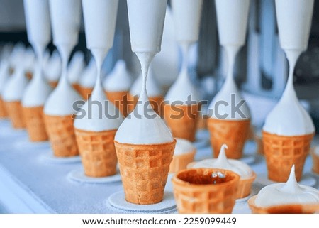 Ice-cream dairy factory - conveyor belt with icecream cones at modern food processing factory. Manufacturing, dairy industry.