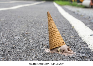 Icecream on the ground. (selective focus)., chocolate icecream cone dropped on the concrete floor and melt on ground. with copy space for text. dirty concept. lost concept.
