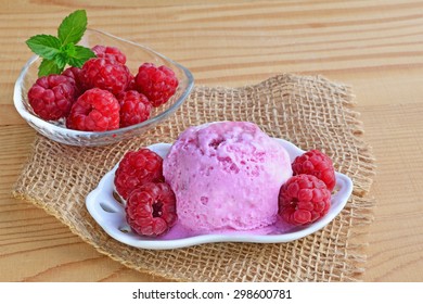 Icecream with ripe raspberries on rustic wooden table.