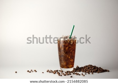 Iced americano coffee with coffee beans on grey background, Glass of black coffee, Beverage at coffee shop.