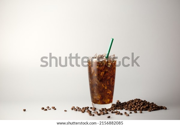 Iced americano\
coffee with coffee beans on grey background, Glass of black coffee,\
Beverage at coffee shop.