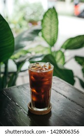 Iced Americano Coffee On Wooden Outdoor Table In Greenery Garden 