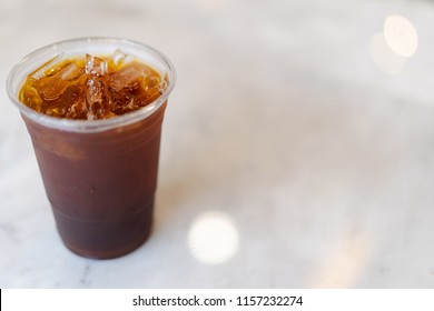 Iced Americano Coffee In Plastic Cup On White Marble Table Background