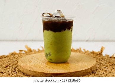 iced avocado coffee, fresh blended avocado poured one shot espresso in a plastic cup on a wooden coaster - Shutterstock ID 2293218685