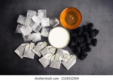 Iced Blackberry Infused Earl Grey Tea Ingredients: Overhead View Of Tea Bags, Creamer, Honey, And Blackberries With Ice Cubes