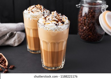 Iced Caramel Latte Coffee In A Tall Glass With Chocolate Syrup And Whipped Cream. Dark Background With Copy Space.