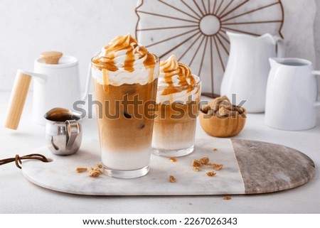 Iced caramel latte in a tall glass with drips of caramel sauce, fancy coffee drink