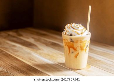 Iced caramel macchiato with whipped cream and caramel drizzle on top on wooden table. - Powered by Shutterstock