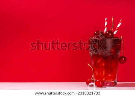 Iced cherry cola drink, Cold summer fruity non-alcohol cocktail with fresh cherries, juice, cola and ice, on high-colored background copy space