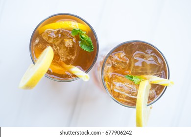 Iced Chilled Drink Tea Cocktail With Lemon Garnish And Yellow Straw On The Balcony White Background Top Down View