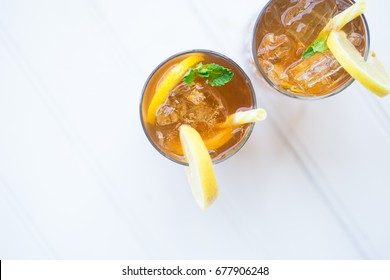 Iced Chilled Drink Tea Cocktail With Lemon Garnish And Yellow Straw On The Balcony White Background Top Down View Copy Space