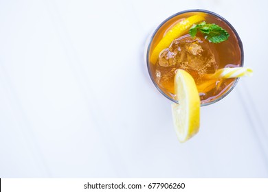 Iced Chilled Drink Tea Cocktail With Lemon Garnish And Yellow Straw On The Balcony White Background Top Down View Copy Space