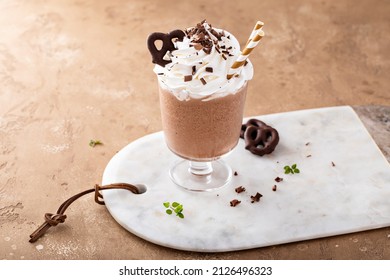 Iced chocolate coffee frappe topped with whipped cream and chocolate pretzels