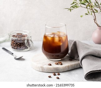 Iced coffee in a glass with ice cubes and grains on a light marble background. The concept of a cold summer drink. - Shutterstock ID 2165399735