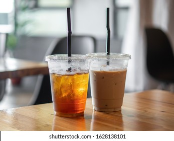 Iced Coffee And Iced Peach Tea In A Wood Table At A Coffee Shop. Cups And Straws Are Made With Plastic.