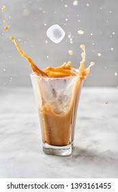 Iced Coffee With Splash On Glass Over Grey Background