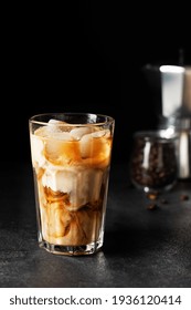 Iced coffee in a tall glass on black background. Cold refreshment summer coffee drink.