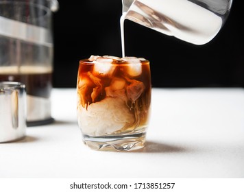 Iced cold brew coffee in a glass with milk poured over. 
