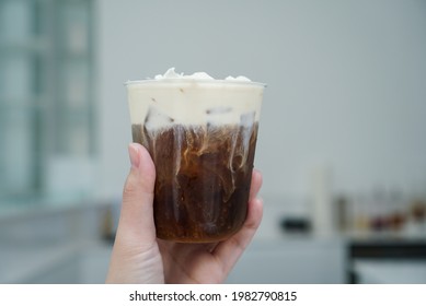 Iced Cold Brew With Milk Foam. Hand Holding A Cup Of Cold Brew Coffee Topped With Milk Foam And White Chocolate. Close Up.