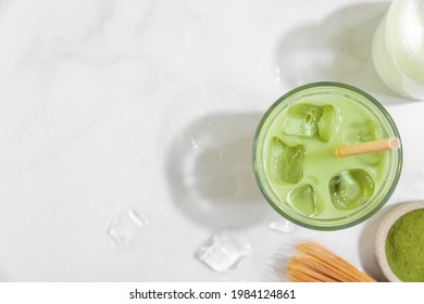 Iced Green Matcha Latte In A Glass On White Background With Hard Shadows. Cold Summer Drink. Top View. Healthy Detox Drink