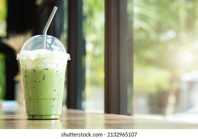 Iced Green Tea With Frothed Milk In A Plastic Cup On A Wooden Table In A Coffee Shop.